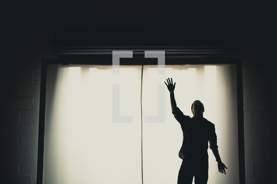 A man with hand raised, worshipping.