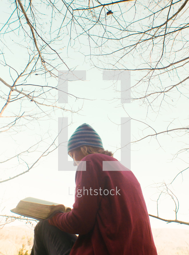 a woman reading a bible outdoors in fall 