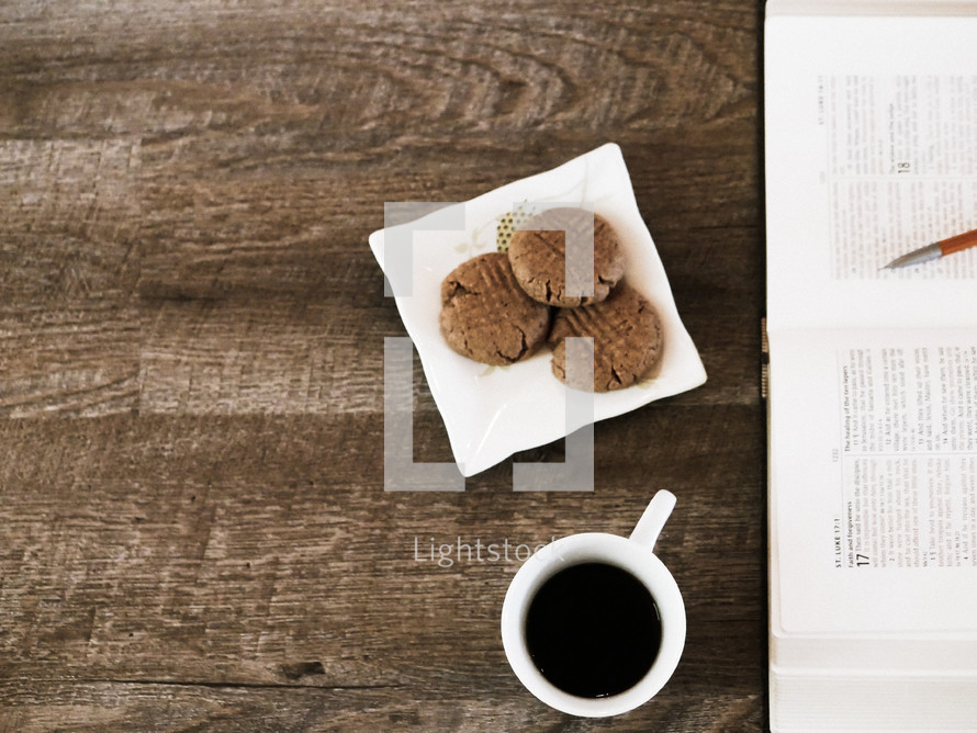 cookies on a napkin, coffee in a mug, and an open Bible 
