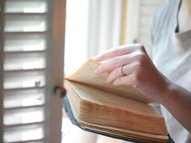 woman reading a Bible at a window seat in a coffee shop 