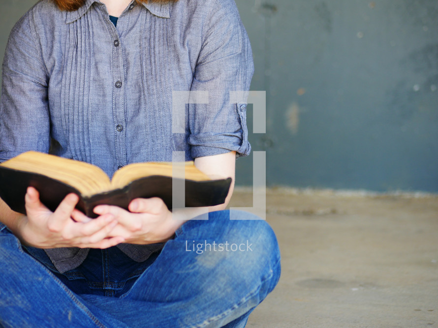 sitting reading a worn Bible 
