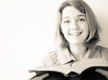 a teen girl reading a Bible in bed 