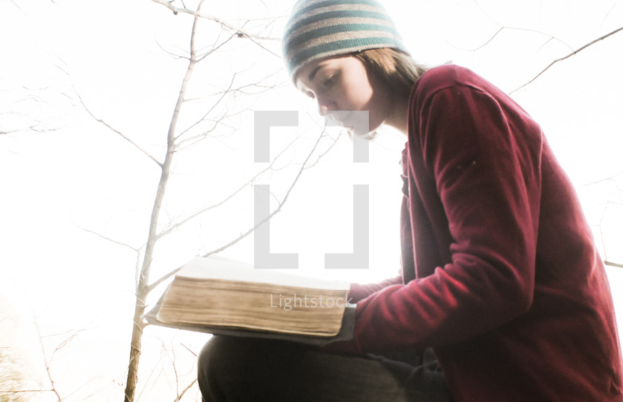 a woman reading a Bible outdoors in fall 