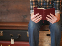 reading a Bible next to suitcases 