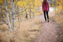 a woman walking down a dirt path in fall 