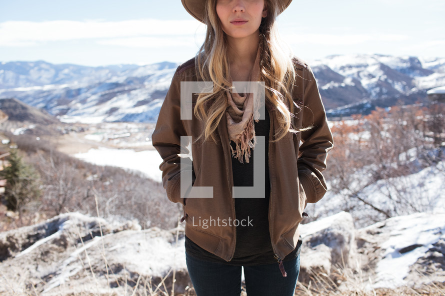 woman in a hat standing on a mountain top 
