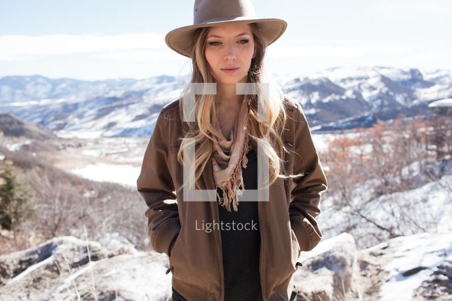a woman in a hat standing on a mountaintop in snow 
