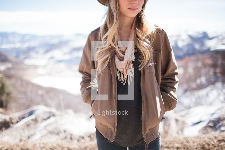 a woman in a hat posing on a mountaintop 