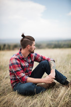 man in a plaid shirt sitting outdoors 