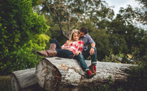 man and woman resting on a fallen tree trunk