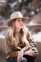 a blonde with long hair in a hat posing outdoors 