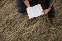 man in a plaid shirt reading a Bible 