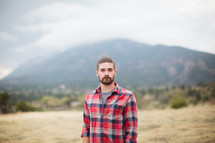 man in a plaid shirt standing outdoors 