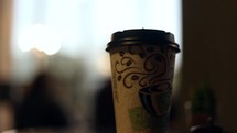 paper coffee cup and hands raised in worship during a worship service 