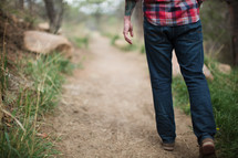 man in a plaid shirt walking on a path 
