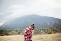 man in a plaid shirt with head bowed in prayer 