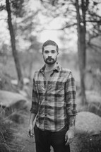 portrait of a man in a plaid shirt standing in a forest 