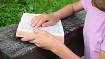 young lady reading a Bible outdoors 
