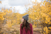 a woman in a wool cap standing in a forest in fall 