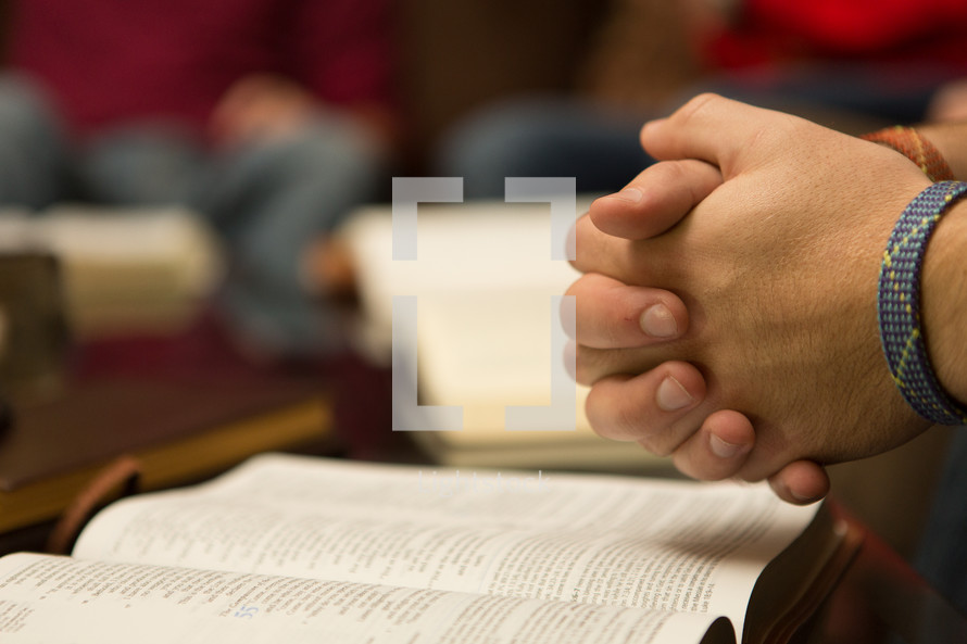 Hands clasped over bible open desk to Isaiah 55, The Compassion of the Lord.