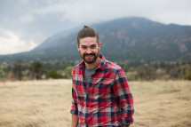 man in a plaid shirt smiling outdoors 
