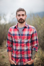 man in a plaid shirt with hands in his pockets 