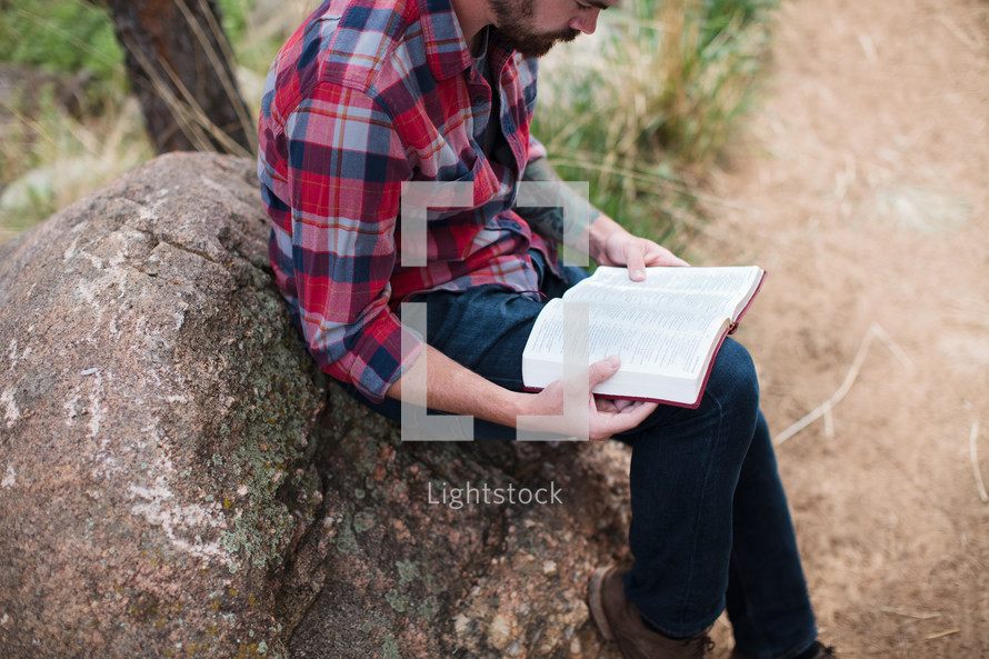 man in a plaid shirt reading a Bible 