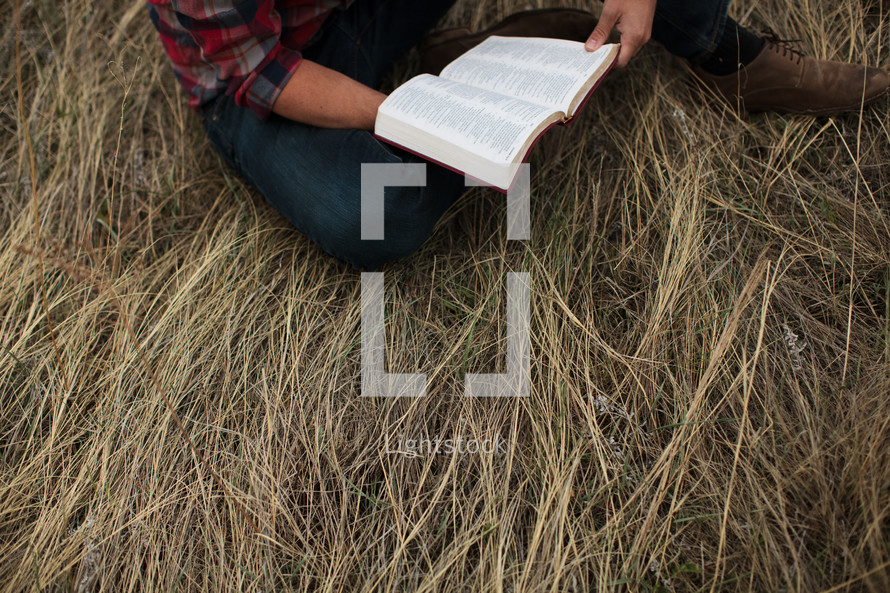 man in a plaid shirt reading a Bible