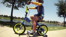 boy riding a bike with training wheels 