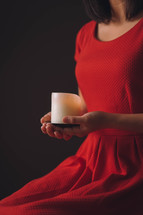 a woman in a red dress holding a candle 