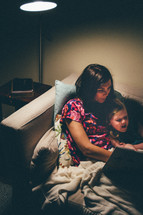 a mother reading to her daughter on the couch 