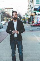 man with a beard posing while standing on a sidewalk 
