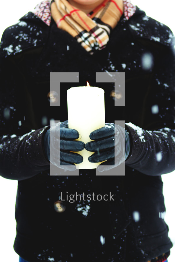 a woman holding a candle outdoors in a winter snow 