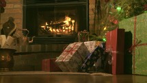 Christmas gifts under the tree by the fireplace.
