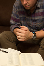 man with his hands in prayer in front of a Bible and journal