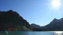 Sun shining on a lake at the foot of a mountain range.