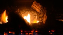 Flames through the logs in a fireplace.