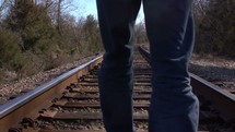 man walking on railroad tracks in slow motion