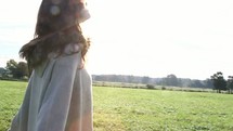 woman standing in a field under warm sunlight 