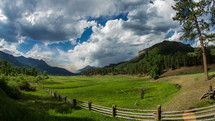 Clouds and shadows moving across a valley of pasture.