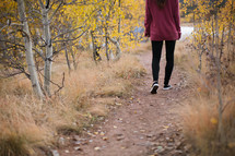 a woman walking down a dirt path 