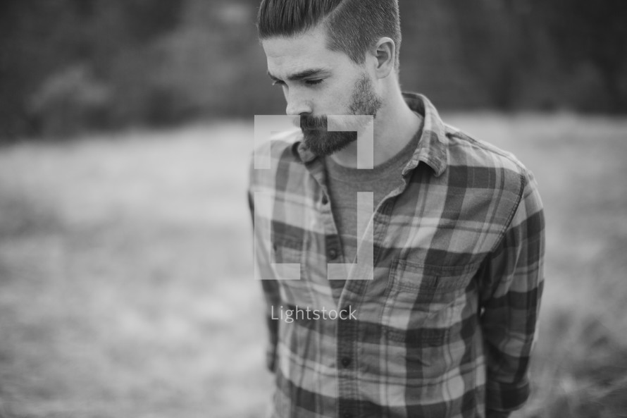 man in a plaid shirt with hands behind his back 