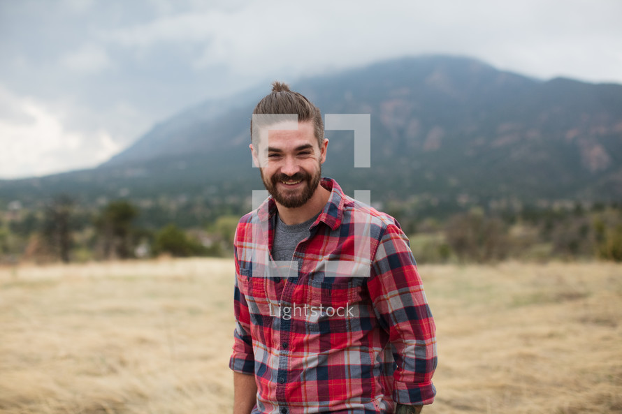man in a plaid shirt smiling outdoors 