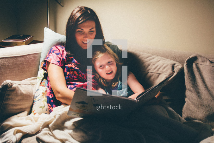 a mother reading to her daughter on the couch 