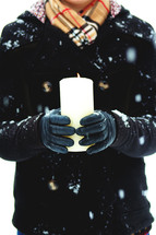 a woman holding a candle outdoors in a winter snow 