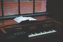 piano and open Bible in a window 