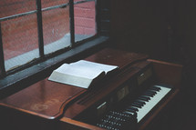 open Bible and piano in a window sill 