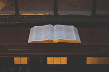 open Bible and piano in a window 