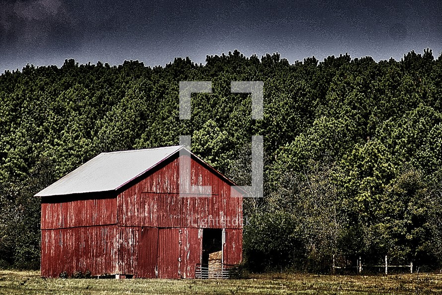 An old red barn at the edge of a forest