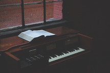open Bible and piano in a window 